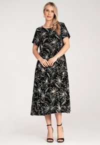 Black dress with short sleeves, featuring white floral embroidery and a flared silhouette. Made of soft fabric, ankle-length with a round neckline.