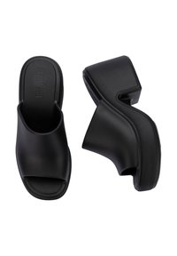 Sandalias de plataforma negras hechas de plástico suave con un diseño de punta abierta amplia. Presenta un talón texturizado para mayor agarre y una ligera curvatura en la forma.
