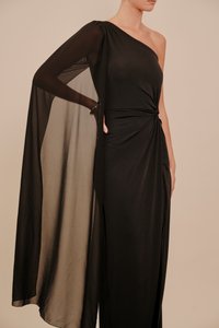 Fekete egyrészes ruha, áramló, átlátszó ujjjal, deréknál csavart csomó részlettel és oldalsó sliccel a mozgás szabadságáért.