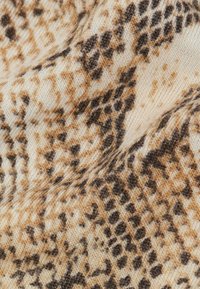 Gebreide stof met bruin en zwart dierenprintpatroon op een beige achtergrond, die de breistekstuur en lichte vouwen toont.