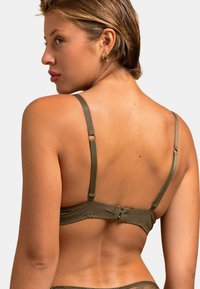 Soutien-gorge vert olive avec bretelles réglables, doté d'une fermeture à crochets et d'une texture de tissu lisse, montrant le design et les détails au dos.