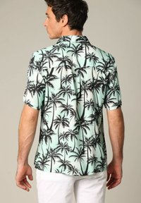 Korte mouw shirt in mintgroen met zwart palmbomenprint; lichtgewicht stof, kraag en een ontspannen pasvorm; beschikt over een achterpand detail.