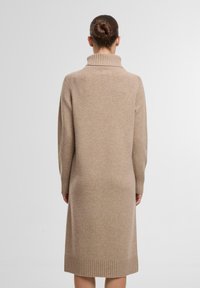 Langes, beige Strickkleid aus weichem Stoff mit hohem Rippkragen und Rippbündchen an den Handgelenken. Knielange. Minimalistisches Design.