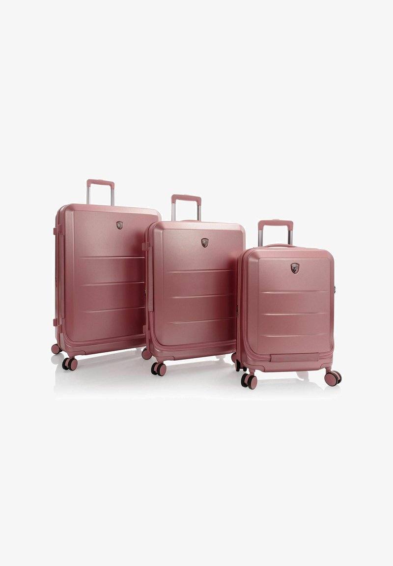 Drei pinkfarbene Hartschalenkoffer mit Rollen und ausziehbaren Griffen; unterschiedliche Größen, glatte Oberfläche und horizontale Linienstrukturen.