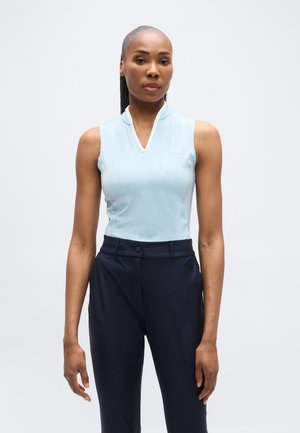 Svetlomodrý tielkový top s vysokým golierom, ktorý má jemný vlnkový vzor. Kombinovaný s tmavomodrými úzkymi nohavicami na mieru.