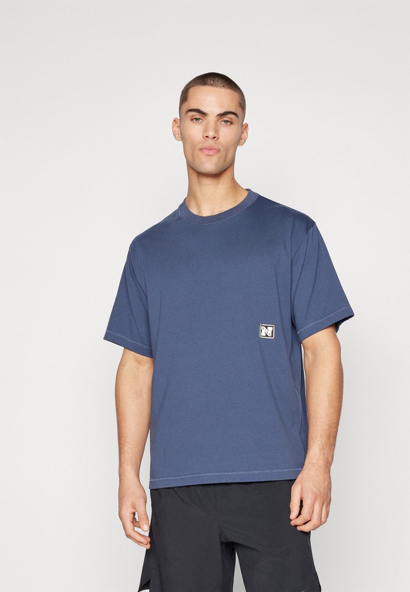 Tricou din bumbac de culoare albastru marin, cu mâneci scurte, gât rotund și o etichetă cu logo rectangular pe pieptul stâng. Include detalii cu cusături contrastante.