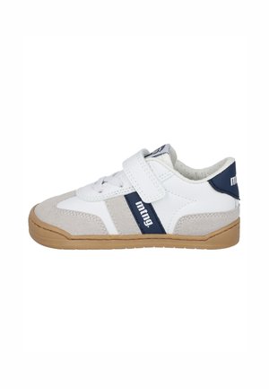 Zapatilla deportiva infantil blanca y gris con detalles azul marino, cierre de velcro, cordones y suela de goma marrón, vista lateral.