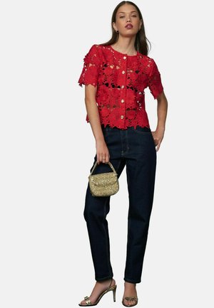 Rød bluse i blonde med blomster mønster, korte ærmer og knaplukning. Matchet med mørke denim jeans og en lille gylden håndtaske. Gyldne hæle sandaler.