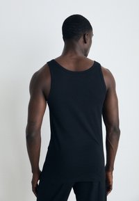 Sort ærmeløs tanktop, lavet af bomuldsstof, figursyet design, rund halsudskæring, glat tekstur, ingen synlige mønstre eller hardware.