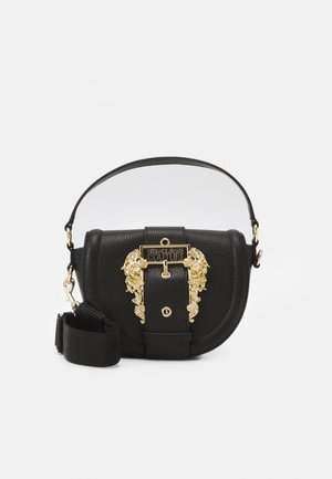 Zwarte leren handtas van Versace Jeans Couture met gouden sierlijke gesp en afneembare band op een effen achtergrond.