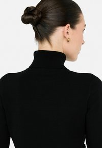 Maglione a collo alto di colore nero con un design aderente. Tessuto a maglia liscia, dotato di un alto colletto e una costruzione semplice e senza cuciture.