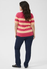 Top de manga corta a rayas en rosa y crema, combinado con jeans azul oscuro. El top presenta rayas horizontales y un escote redondo.