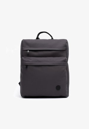 Sac à dos carré gris foncé avec deux poches avant zippées et un petit logo rond près du coin inférieur droit.