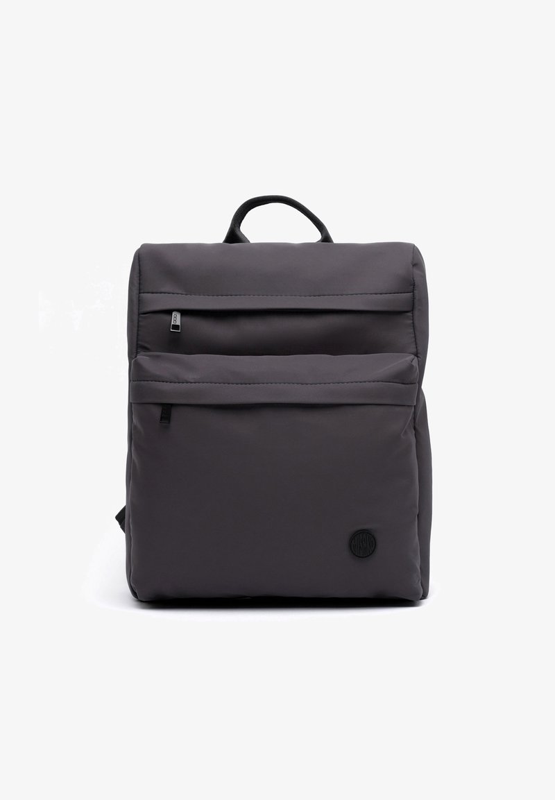 Sac à dos carré gris foncé avec deux poches avant zippées et un petit logo rond près du coin inférieur droit.