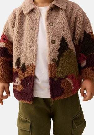 Enfant portant une veste polaire colorée, boutonnée et texturée par-dessus une chemise blanche et un pantalon cargo vert olive.