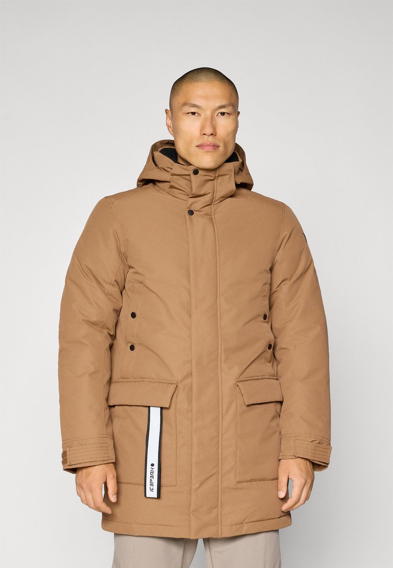 Brun polstret parka-jakke med hette, med trykknapplukking, to frontlommer og et sidelabel-detalj. Glatt tekstur og isolert design.