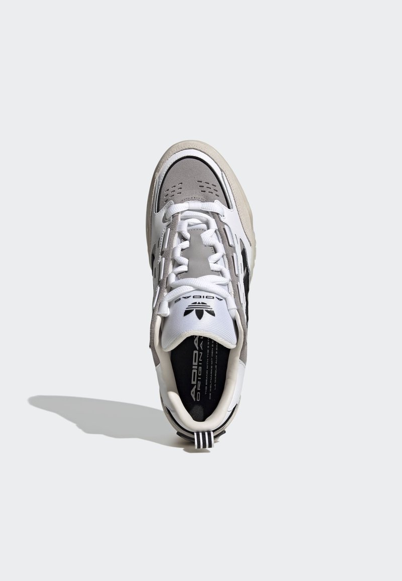 Białe i szare sneakersy z górą z teksturowanej zamszowej i skórzanej, akcentami z perforacji, płaskimi białymi sznurówkami i czarnym logo na języku.