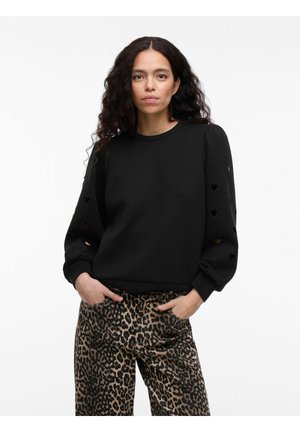 Sweatshirt noir avec manches bouffantes présentant des découpes en forme de cœur, associé à un pantalon en imprimé léopard. Tissu doux, coupe décontractée.