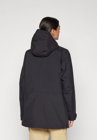 Zwarte waterdichte jas met capuchon, met een relaxte pasvorm, naaddetails, lange mouwen en knoopmanchetten.