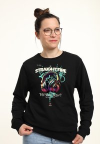 Zwarte sweatshirt met een kleurrijke hoofdtelefoonafbeelding, tekst met "STRAIGHTFIRE" en "TROPICAL TWIST", met een ontspannen pasvorm en ribbelmanchetten.