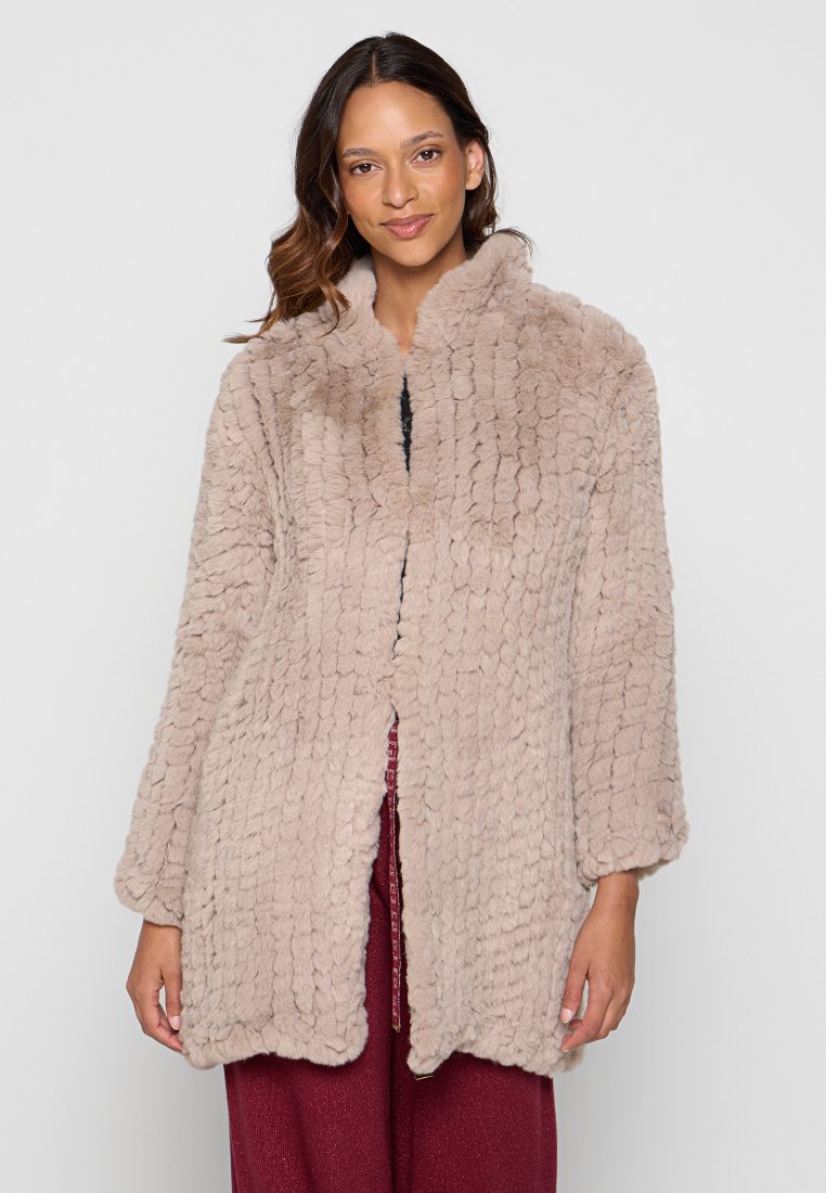 Płaszcz z sztucznego futra w miękkim beżu o teksturowanej, puszystej powierzchni. Posiada okrągły kołnierz i otwarty przód. Długie rękawy i luźny krój.