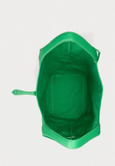 Plaša zaļa ādas soma ar auduma oderējumu un ar sprādzi aizdarāmu siksnu, skatīta no augšas, rādot tās tukšo iekšpusi.