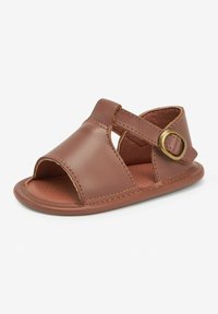 Brun läder sandal med öppen tå och häl, har korsrem och justerbar spänne, avslutad med kontrasterande sömmar.