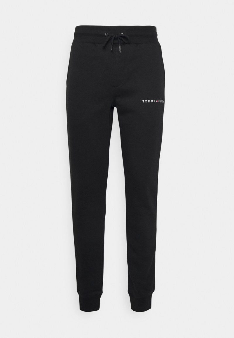 Černé tepláky vyrobené z měkké tkaniny, s elastickým pasem na stahování a žebrovanými manžetami. Logo "TOMMY HILFIGER" vytištěné bílou barvou na boku.