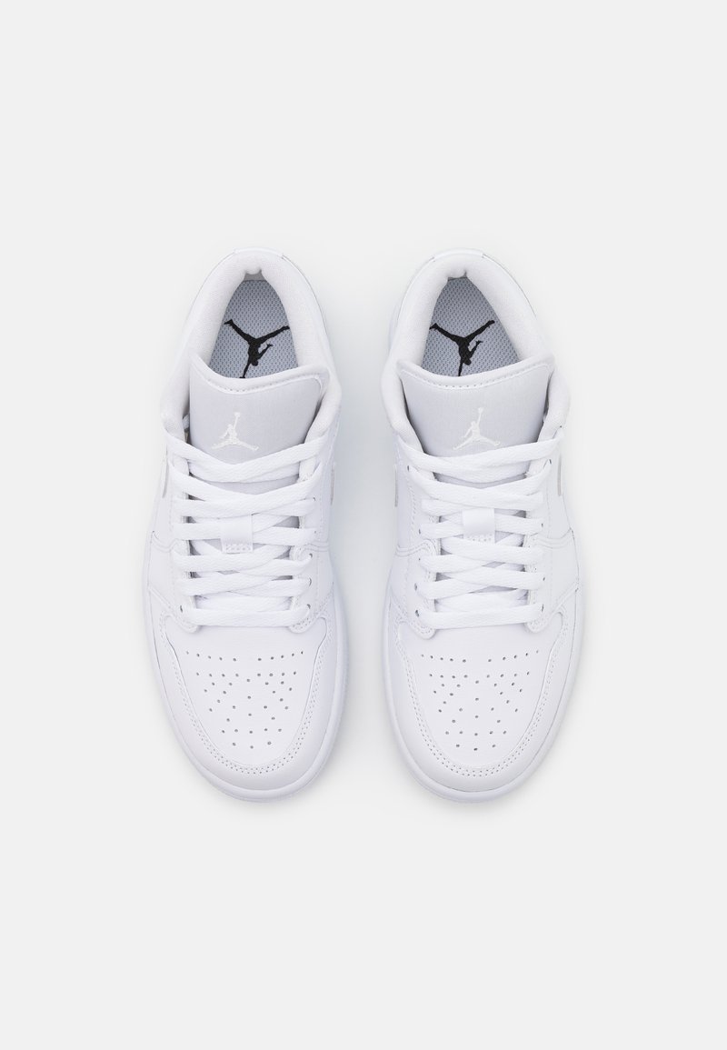 Baskets athlétiques en cuir blanc avec une boîte à orteils perforée, des lacets plats et des accents gris. Présente un logo noir emblématique sur la languette et la semelle intérieure.