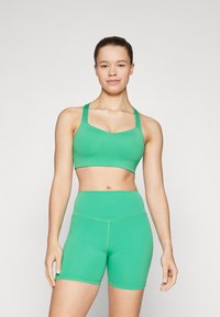 Grønn sømløs sports-bh med brede stropper og matchende høyt midje shorts, med elastisk materiale og glatt tekstur.