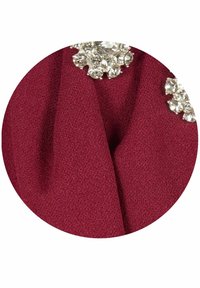 Burgundská tkanina s texturovaným povrchem, zdobená průhlednými drahokamy na rameni, které zvýrazňují elegantní design.
