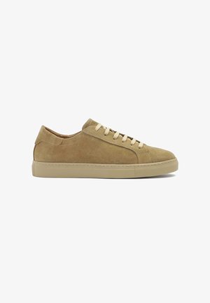 Baskets en daim beige à profil bas, avec des lacets plats, une pointe arrondie et une semelle en caoutchouc durable. Des coutures discrètes accentuent le design.