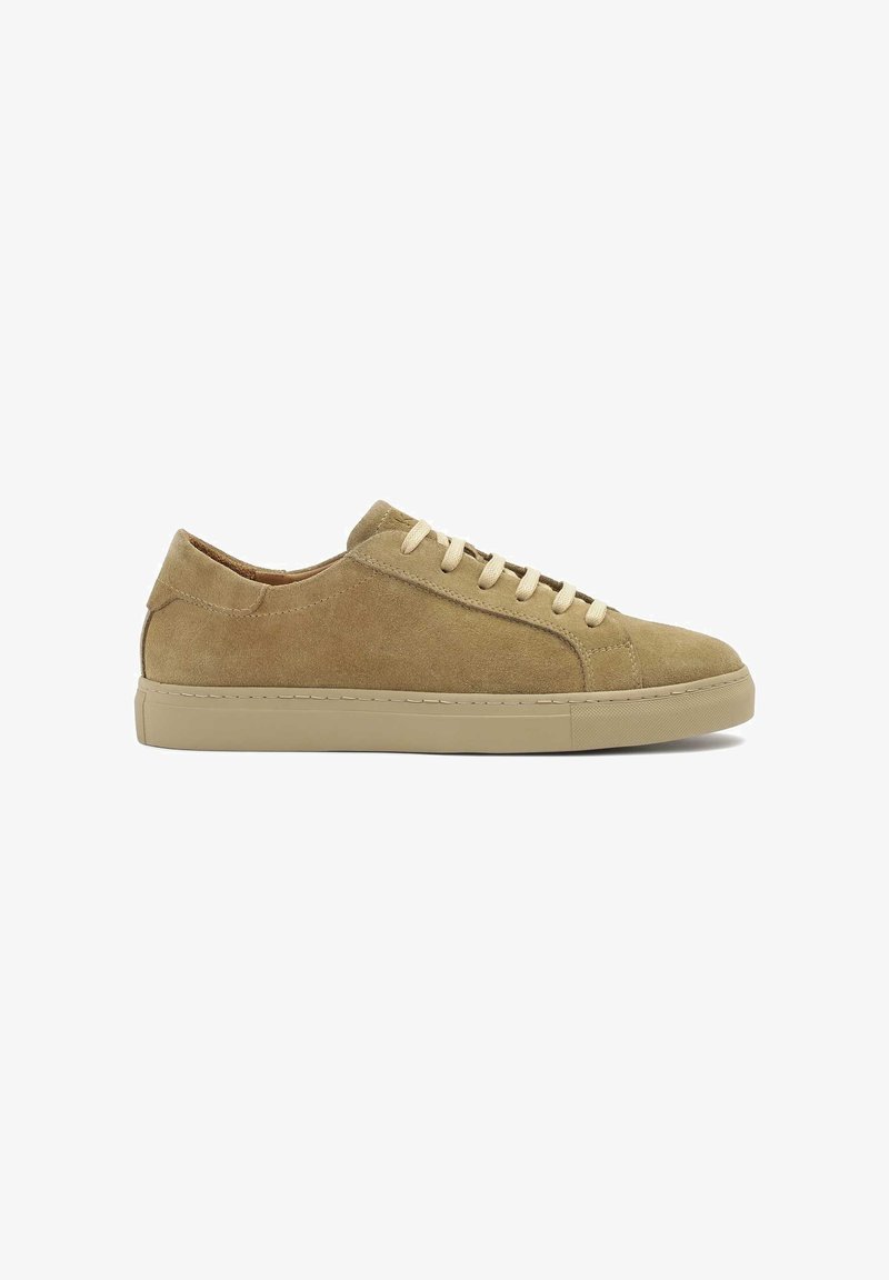 Beige sukadest sneaker madala profiiliga, millel on lapikud paelad, ümar nina ja vastupidav kummist tall. Diskreetne õmblus rõhutab disaini.