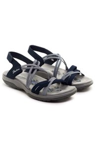 Sandali Skechers blu e grigi con cinturini incrociati, suole imbottite e suola flessibile. Tessuto morbido e motivi geometrici sulla soletta.