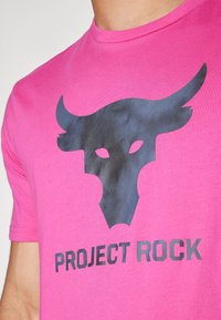 Rosa bomull t-skjorte med svart okse-logo og teksten "PROJECT ROCK" i fet skrift. Korte ermer og design med rund hals.