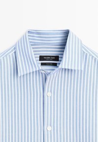 Camicia button-up a righe blu chiaro e bianche con colletto classico e due bottoni bianchi, realizzata in tessuto italiano. Etichetta visibile.