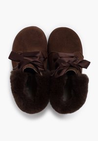 Pantofole in suede marrone con un morbido risvolto in pelliccia sintetica marrone scuro e nastri in raso. Il design è arrotondato e accogliente.