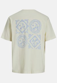 Kræmfaret bomulds-T-shirt med korte ærmer, prydet med et lysblåt blomsterdesign på bagsiden i cirkulære og diamantformer.