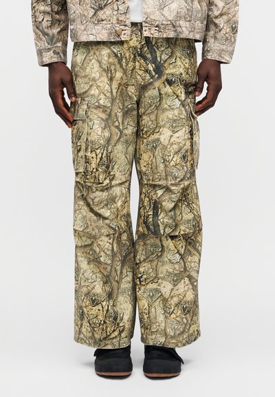 Παντελόνια cargo καμουφλάζ με συνδυασμό πράσινων, καφέ και μπεζ αποχρώσεων, υφή υφάσματος, πολλαπλές τσέπες και άνετη εφαρμογή.