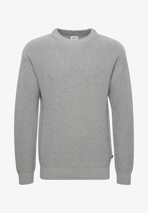 Pull en maille gris avec un col rond, des manches longues, des poignets et un ourlet côtelés. La texture du tissu est épaisse et texturée. Petite étiquette sur le côté.
