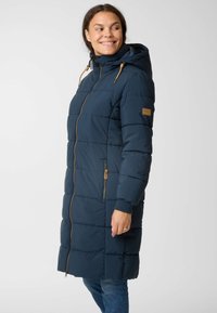 Marineblauwe pufferjas met een capuchon, een volledige rits, elastische manchetten en tan accenten. Kenmerkt zich door een geborduurd textuur en zijzak.