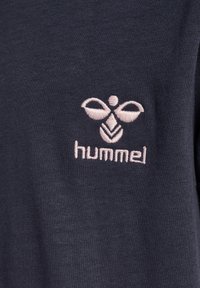 Dunkelblaues T-Shirt mit glattem Material, das ein hellrosa gesticktes Logo von "hummel" und ein symmetrisches Schmetterlingsdesign über dem Text zeigt.