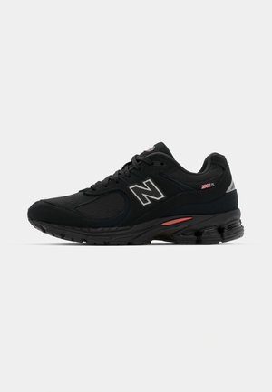 Schwarzer Sportschuh aus Mesh- und Wildledermaterialien, ausgestattet mit einer dicken Sohle, gepolstertem Schaftrand und reflektierenden Akzenten. Modellnummer 2002R.