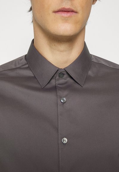 Camisa abotoada cinza escuro com colarinho clássico, textura suave e dois botões pretos à frente, apresentando detalhes de costura discretos.