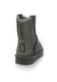 Botín de ante gris hasta el tobillo con punta redondeada, forro de pelo y dos botones decorativos en el lado exterior. Suela de goma para mayor tracción.