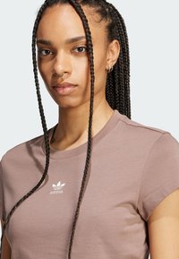 Hnědá bavlněná tričko s vroubkovaným kulatým výstřihem a krátkými rukávy, na hrudi s vyšitým bílým logem Adidas.
