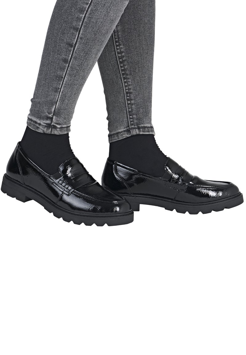 Mocassins en cuir verni noir avec une finition texturée, dotés d'un bout arrondi et d'une épaisse semelle en caoutchouc, associés à un jean gris ajusté.