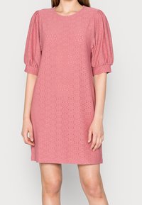 Lyhyt vaaleanpunainen mekko, jossa on puffihihat, pyöreä kaula-aukko ja kyynärpään yksityiskohtia, jotka tuovat tekstiiliin lisärakennetta.