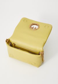 Borsa a mano gialla in pelle con un accento di hardware dorato rotondo, chiusura a zip e scomparti interni. Esterno testurizzato, forma rettangolare.