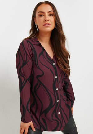 Long-sleeve button-up shirt in maroon with black wave patterns, featuring a textured fabric and metallic buttons along the front.